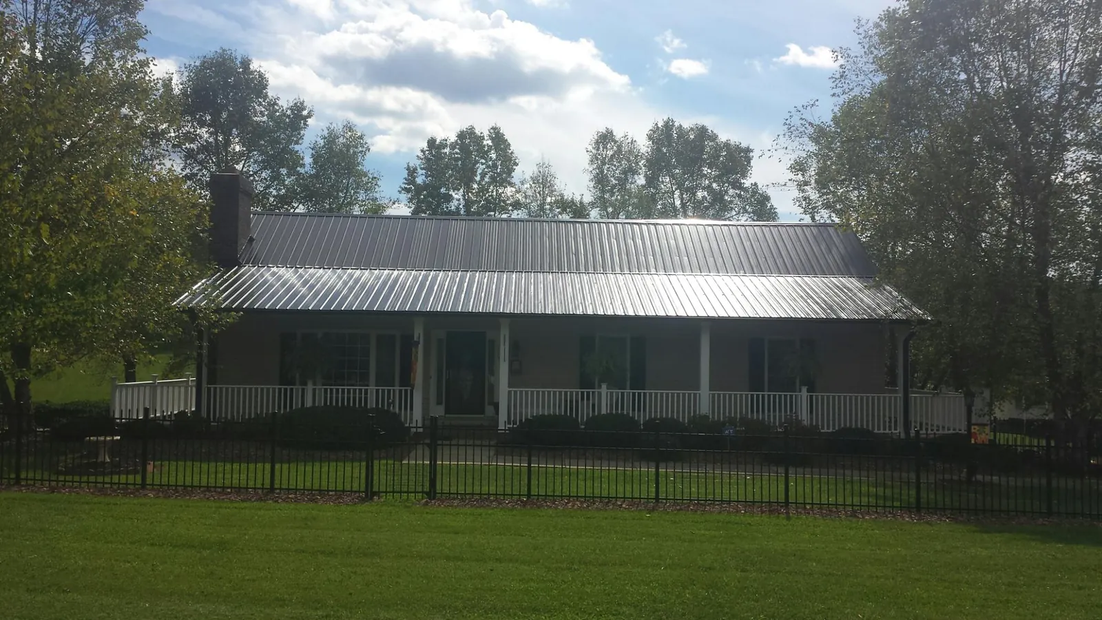Gray metal roof on a brick ranch with a full width front porch — Gutter Guard Installation work by our crew in Rutherford College