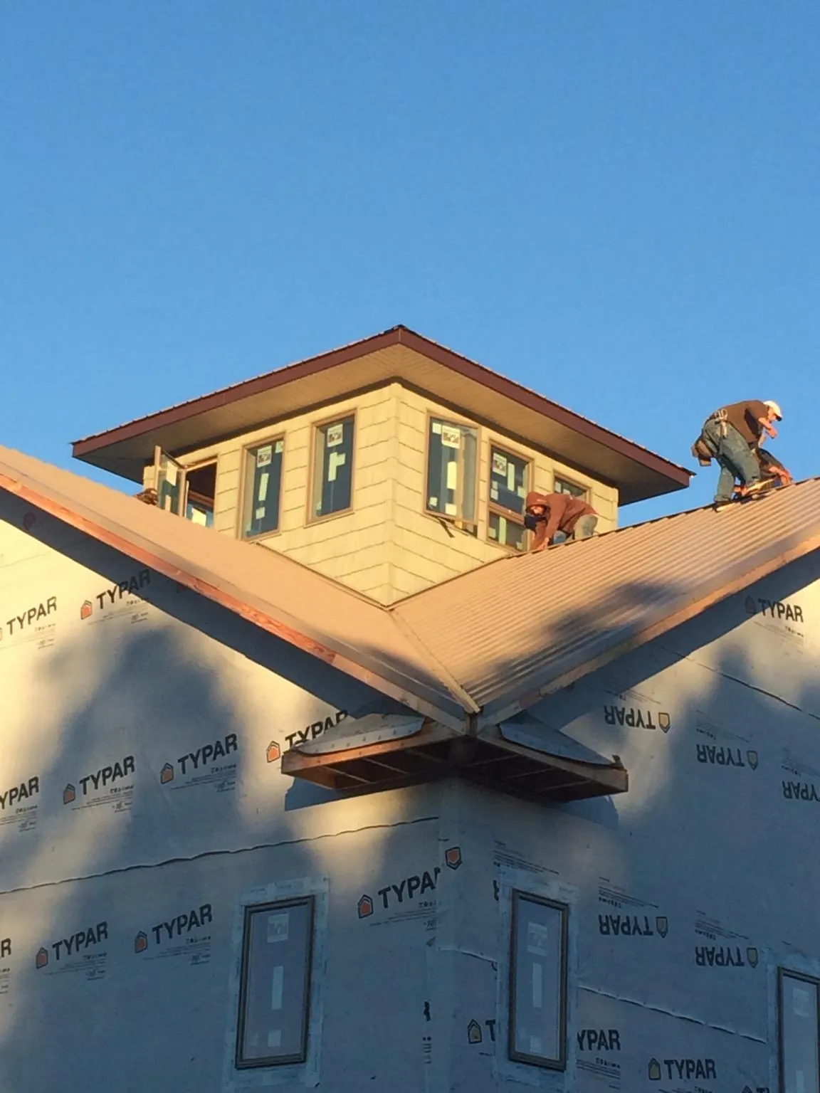 Roofers working around a rooftop cupola on a new metal roof at sunset — Roof Waterproofing in Rutherford College by Roofing Brothers